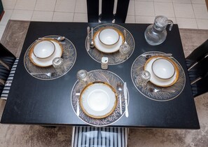 Ein Esstisch, gedeckt mit vier Tellern, Besteck und einer Glas-Karaffe.