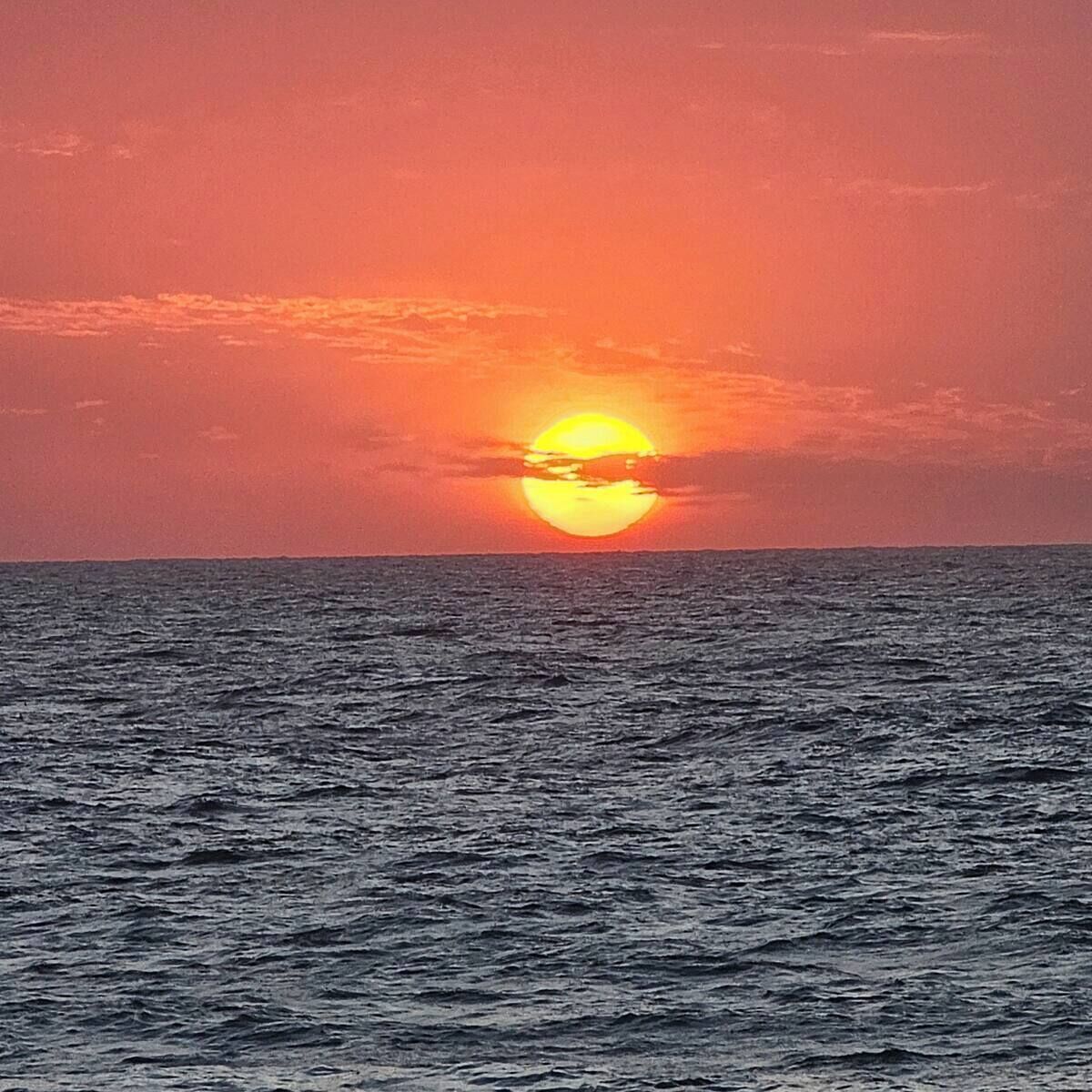 A sunset over the ocean with a clear sky.