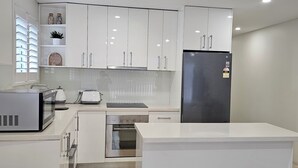 Eine moderne Küche mit weißen Schränken, einem Edelstahl-Kühlschrank, einer Mikrowelle, einem Toaster und einem Backofen.