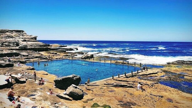 Ein Pool, umgeben von felsigem Gelände, mit Blick auf den Ozean.