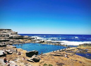 En pool omgivet af stenede omgivelser med udsigt til havet.