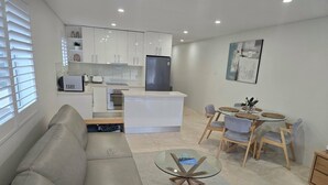Ein modernes Wohnzimmer mit Sofa, einem Glastisch und einem Essbereich mit rundem Tisch und Stühlen.