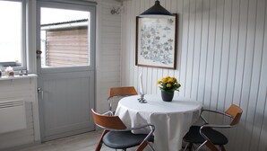 Un comedor con una mesa redonda, cuatro sillas, una vela y un mapa enmarcado de Dinamarca en la pared.