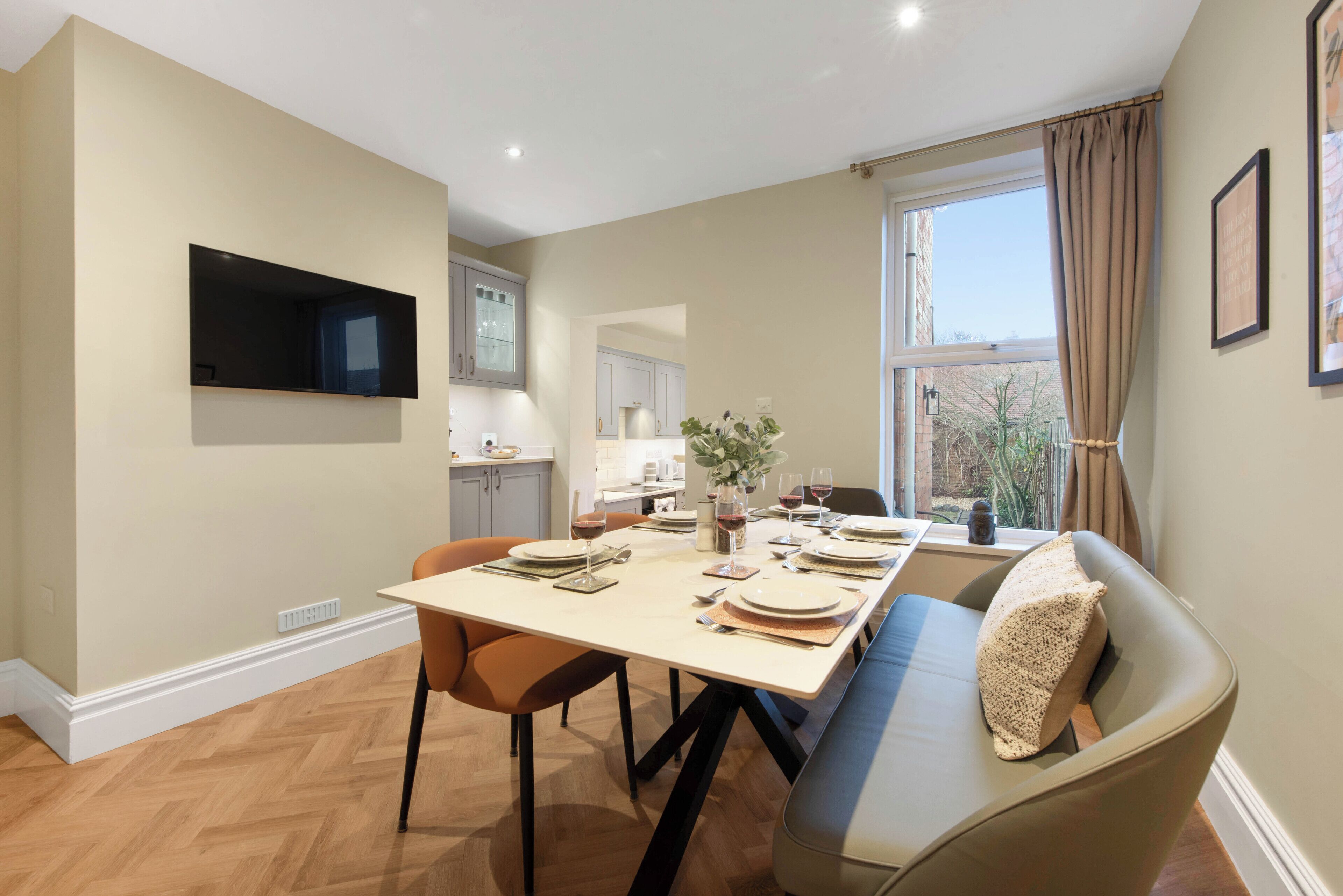 Un coin repas avec une table dressée pour quatre personnes, un canapé et un téléviseur fixé au mur.