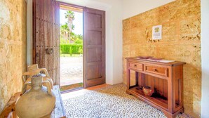 A room with a wooden door, a tiled floor, a wooden cabinet, and a large vase. - Finca Roig Petit | Mallorcan Charm in Pollensa | Private Pool & Tranquil. (Pollensa)