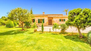 A stone house with a tiled roof, surrounded by a well-maintained garden with various trees and shrubs. - Finca Roig Petit | Mallorcan Charm in Pollensa | Private Pool & Tranquil. (Pollensa)