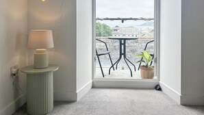 Een kamer met uitzicht op een balkon, een neonbord, een lamp en een plant in pot.
