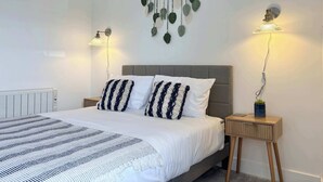 Een slaapkamer met een bed, twee nachtkastjes, een wandlamp en een radiator.