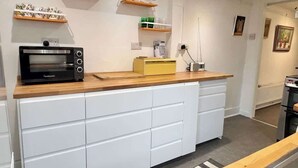 A modern kitchen with white cabinetry, a black microwave, and wooden countertops. - Unique Artsy Home on the Penzance Promenade (Penzance)