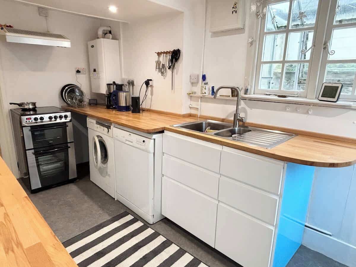 Een praktische keuken met een kookplaat, oven, wasmachine en spoelbak.