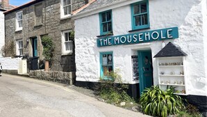 Een wit gebouw met blauwgroene accenten en een bord waarop 'THE MOUSEHOLE' staat.