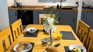 Een praktische keuken met een eethoek, met daarin een spoelbak, kastjes en een klok.