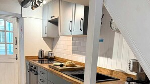 Een keuken met grijze kastjes, een houten aanrecht en een RVS-spoelbak.