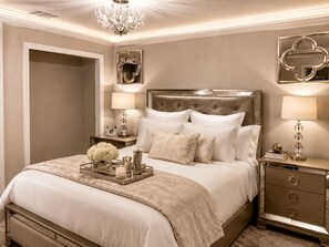 A bedroom with a large bed, two bedside tables, a chandelier, and a mirror on the wall. - Domain District Gem • Stylish 2BR/2BA • Perfect Location (Austin)