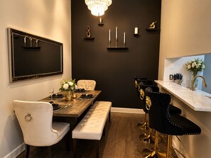 A dining area with a wooden table, white upholstered chairs, a bench, and a chandelier. - Domain District Gem • Stylish 2BR/2BA • Perfect Location (Austin)