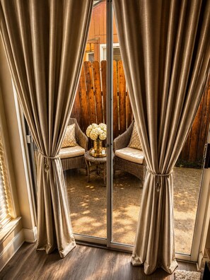 A room with a sliding glass door, wicker furniture, and a vase with flowers. - Domain District Gem • Stylish 2BR/2BA • Perfect Location (Austin)