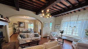 A spacious living room with a high ceiling, white sofas, a wooden coffee table, and a chandelier. - Stunning  villa with private pool, WIFI, A/C, TV, veranda, pets allowed and panoramic view (Torre)