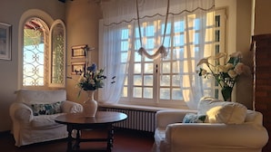 A cozy living room with two white armchairs, a wooden table, and a vase of flowers. - Stunning  villa with private pool, WIFI, A/C, TV, veranda, pets allowed and panoramic view (Torre)