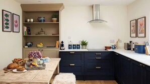 Une cuisine moderne avec des meubles bleu foncé, un plan de travail blanc et une lucarne au-dessus.