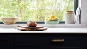 Una encimera de cocina con una hogaza de pan, un bol de limones y un tarro de miel.