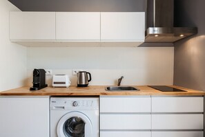 Une cuisine compacte équipée d’un lave-linge, d’un grille-pain, d’une bouilloire et d’un évier.