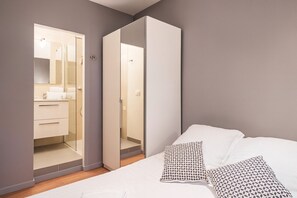 Une chambre à coucher avec un lit, des oreillers et une armoire dotée d’un miroir.