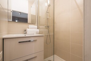 Une salle de bain moderne avec une douche à parois de verre, un lavabo avec un miroir et un porte-serviettes.