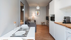 Une cuisine moderne avec des meubles blancs, un plan de travail en bois et une machine à café.