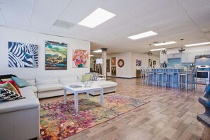 A spacious living area with a white sofa, a coffee table, and colorful artwork on the walls. - HUGE 5000 sqft condo 2 blocks Beale, 10 beds, 2king 8queen, 3 bath, parking lot (Memphis)