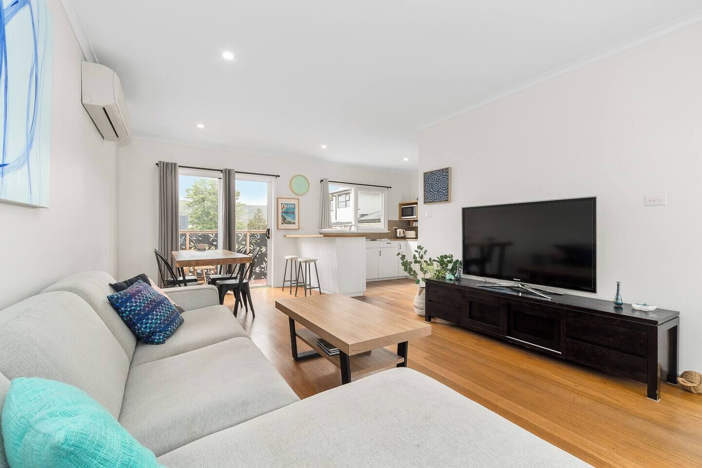 A modern living room with a sofa, a coffee table, a TV, and a dining area with a table and chairs.