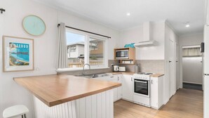 A modern kitchen with white cabinets, a wooden countertop, a built-in oven, and a microwave. - The Shamrock - 700m to the Beach (Rosebud)