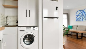A compact kitchen with a built-in washer and dryer, a wooden countertop, and a modern design. - The Shamrock - 700m to the Beach (Rosebud)