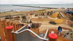 A playground with a slide, surrounded by wooden structures and a sandy area. - The Shamrock - 700m to the Beach (Rosebud)