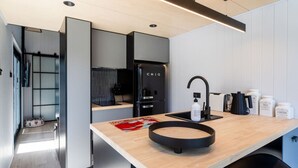 Een moderne keuken met een houten aanrecht, een zwarte spoelbak en koffiezetapparatuur.