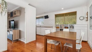 Eine moderne Küche mit weißen Schränken, einem Holzespeisetisch und einem an der Wand montierten Fernseher.
