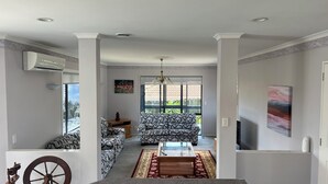 A spacious living area with a patterned sofa, a glass coffee table, and a decorative rug. - Private Family Home With Four Bedrooms (Manukau)