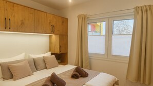 A bedroom with a bed, wooden wardrobe, and a window with curtains. - New Tiny House - cozy, private, family-friendly! (Hessisch Lichtenau)