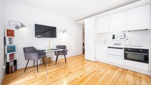 Une cuisine moderne avec des meubles blancs, un four encastré et un coin repas comprenant une table et des chaises.