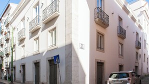 Un immeuble doté de plusieurs balcons, un panneau indiquant un passage pour piétons et une voiture garée.