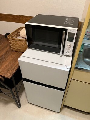 A compact microwave oven with a digital control panel, placed on a wooden table next to a wicker basket. - 30sec walk to Tsutenkaku/1 stop to Namba Sta./AH48 (Ebisu Higashi Naniwa-Ward,Osaka City)