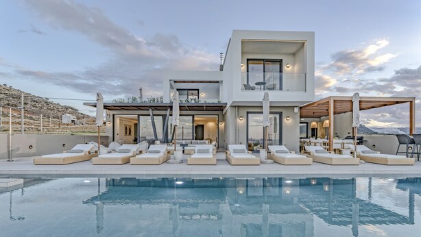 Uma casa moderna de dois andares com piscina, área de estar externa e vista para as montanhas.