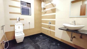 A bathroom with a toilet, bidet, and sink. - Hotel Meera Regency (Chiplun)