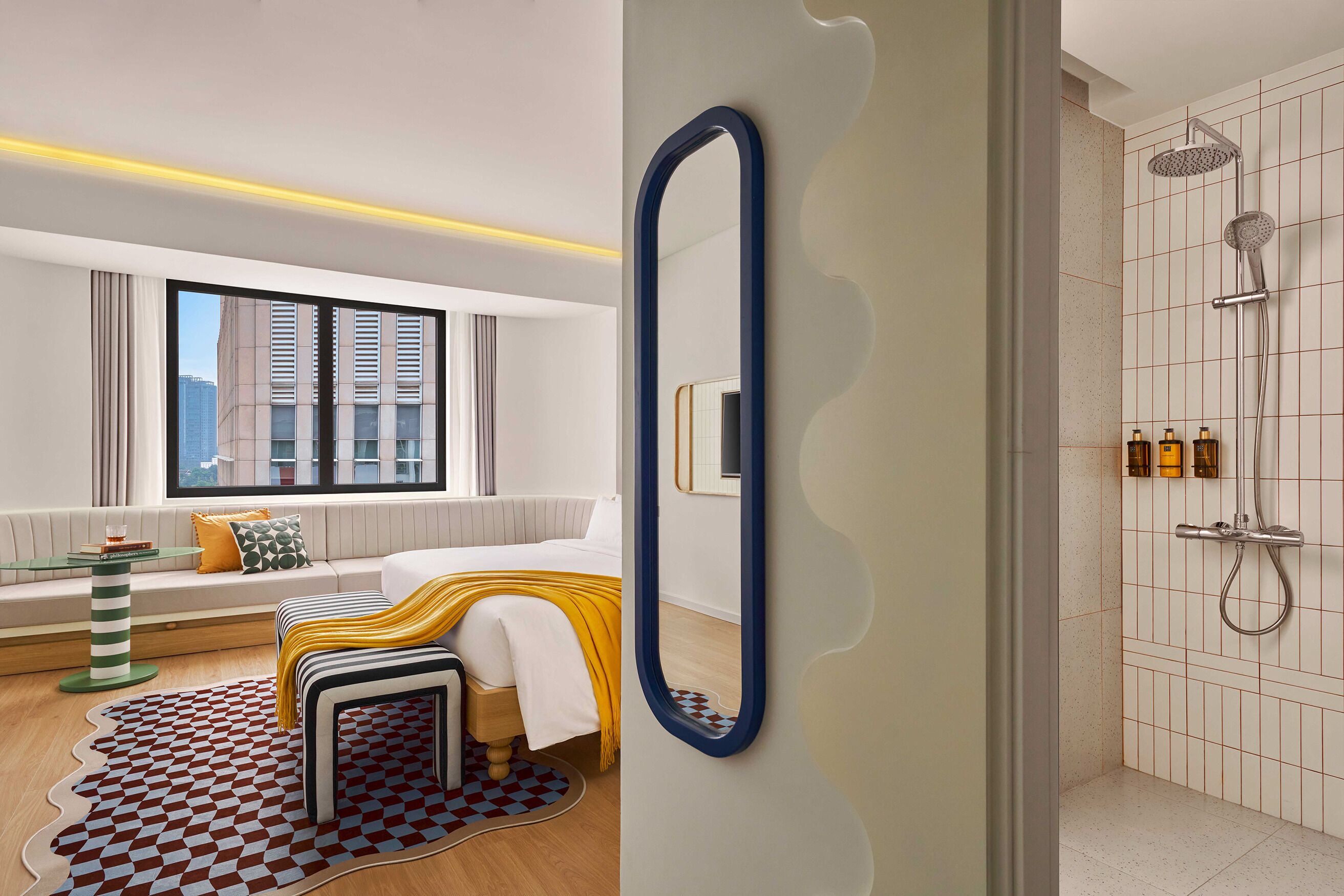 A modern bathroom with a shower, a large mirror, and a view of the city through a window.