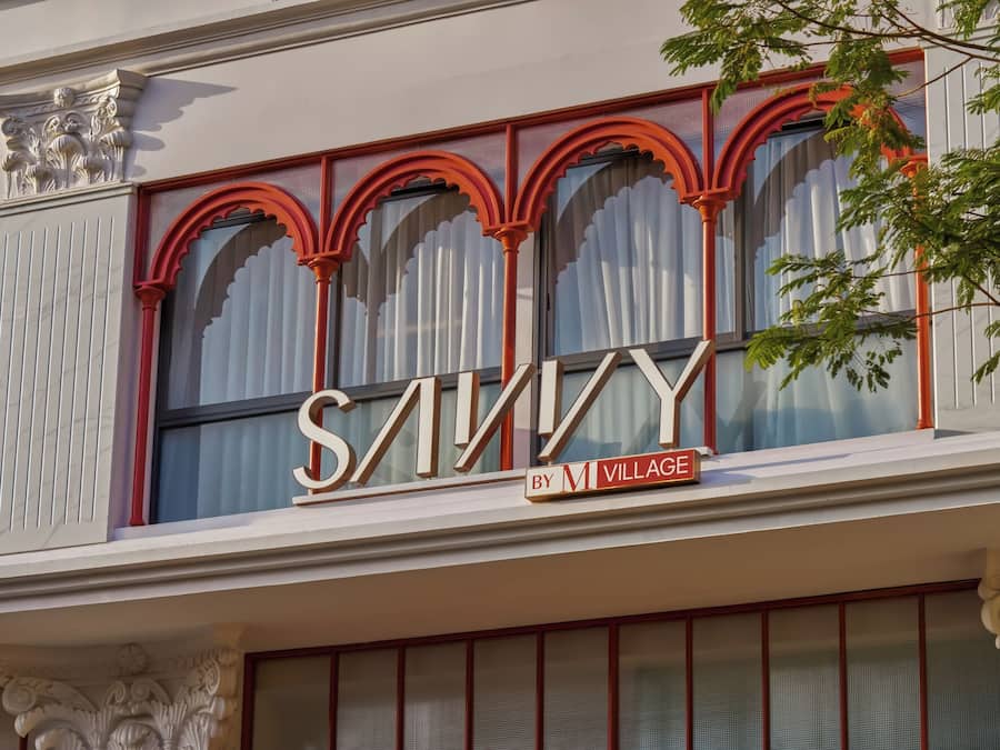 A building facade with large arched windows and a prominent sign that reads 'SAVINY BY M VILLAGE'.