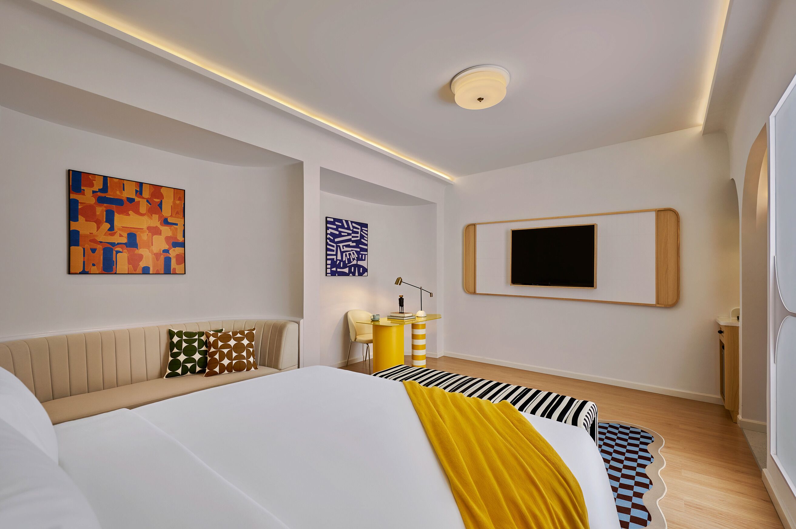 A modern bedroom with a large bed, a flat-screen TV, and abstract art on the walls.