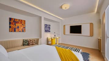 A modern bedroom with a large bed, a flat-screen TV, and abstract art on the walls.