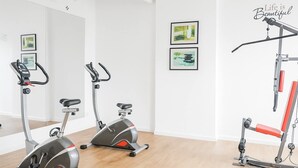 Et moderne fitnessrum med to motionscykler, en bænkpres og to indrammede kunstværker på væggen.