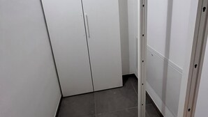 A corner of a room with a white wardrobe, a metal rack, and a tiled floor. - App. Red (Borgonovo)