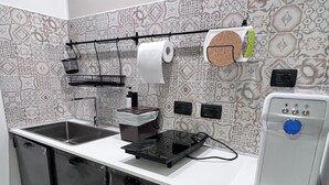 A modern kitchen with a white countertop, black cabinets, a coffee machine, a water dispenser, and a patterned backsplash. - App. Red (Borgonovo)