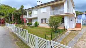 A two-story residential building with a balcony on the upper floor, a small front yard, and a gated entrance. - Pleasant apartment in Rosolina Mare with balcony (Rosolina Mare (RO))